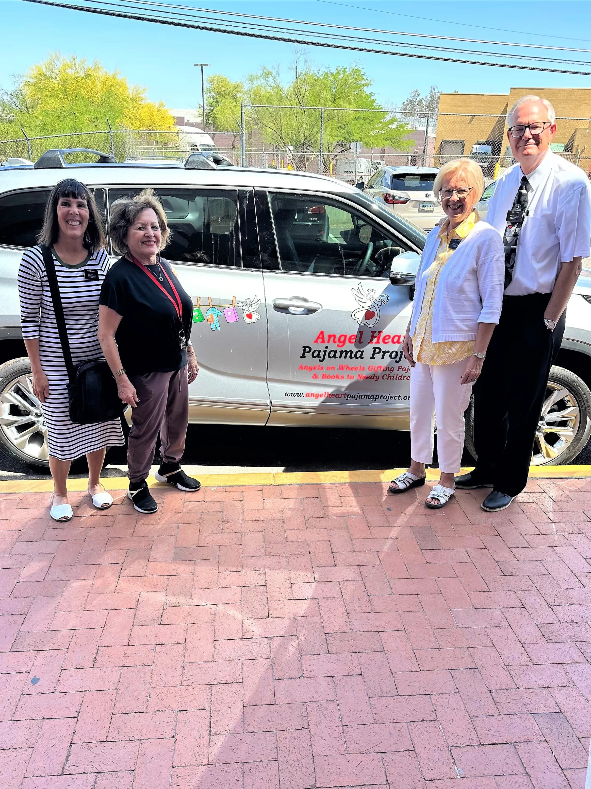 Volunteers standing beside the Angel Heart Pajama Mobile before a delivery