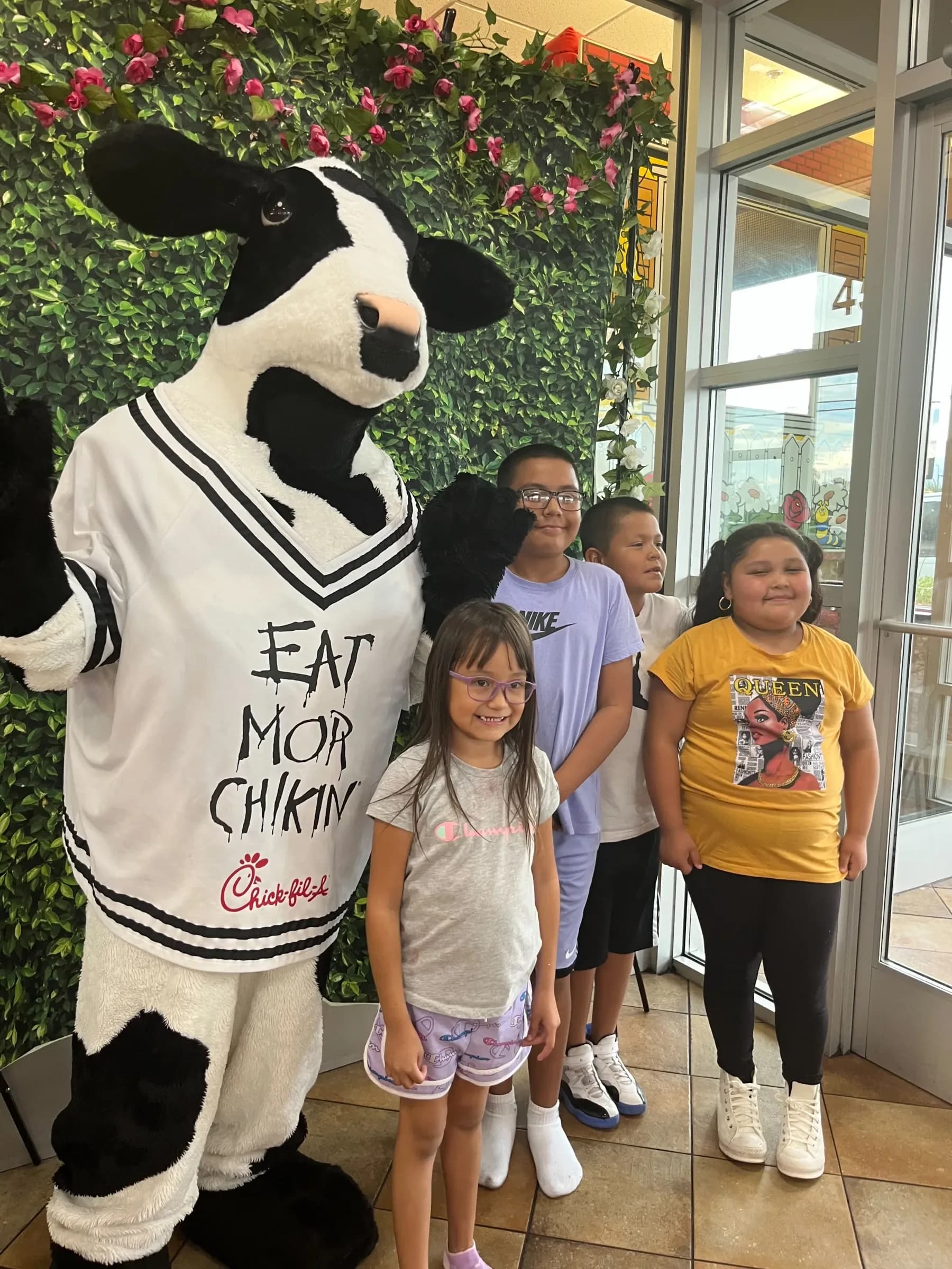 Children posing with the Chick-fil-A cow mascot at an Angel Heart event