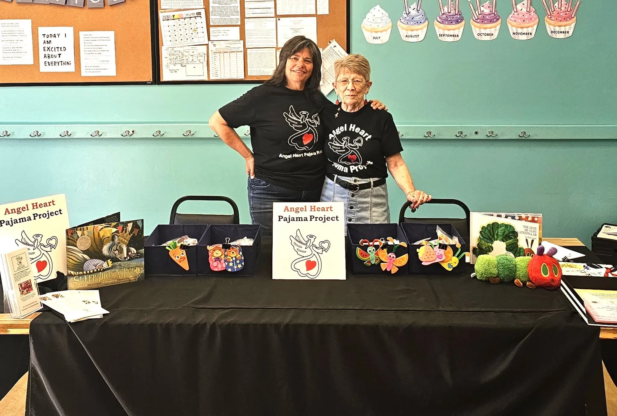 Angel Heart volunteers at an outreach table displaying books and pajamas